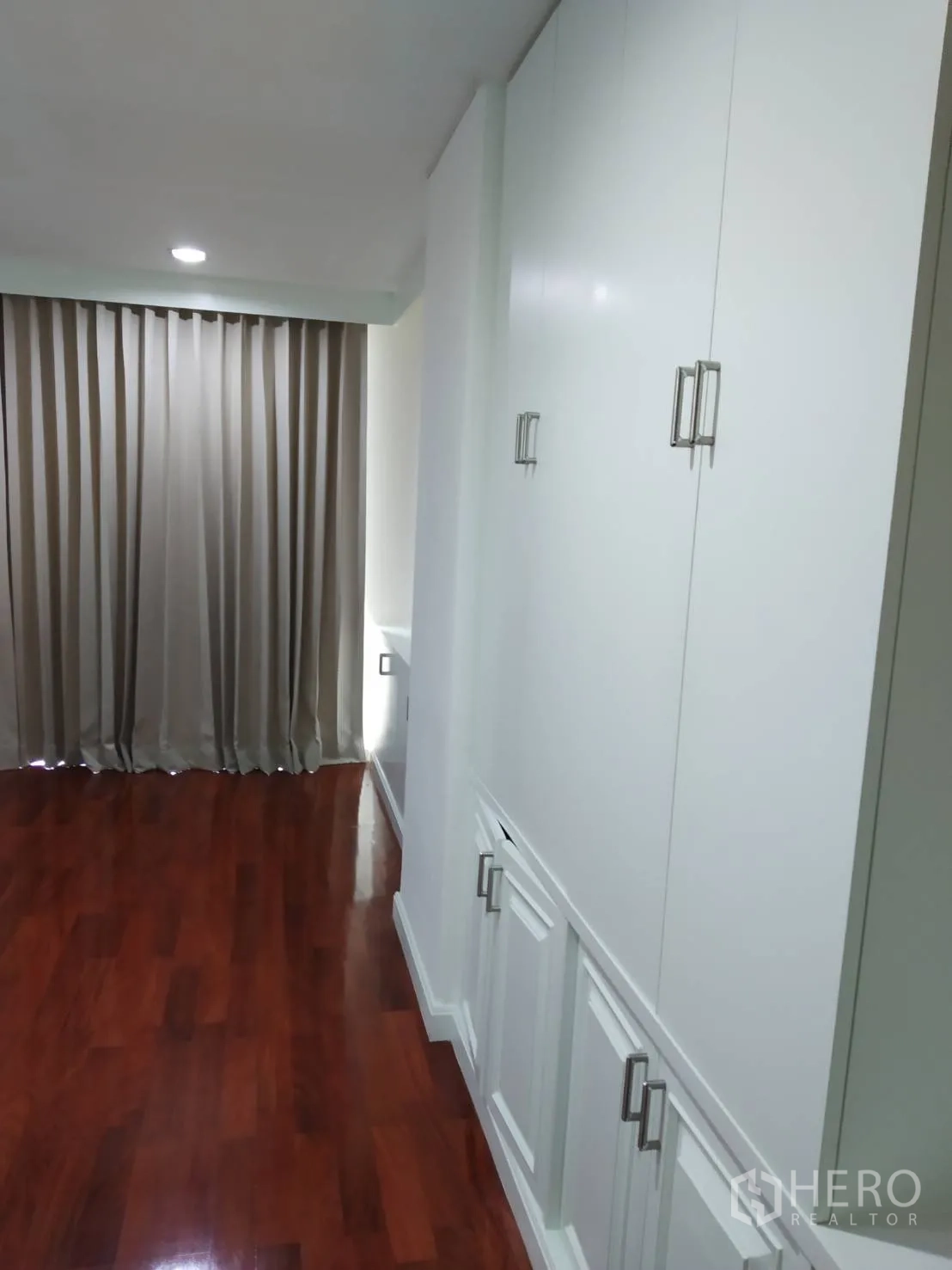 Condominium for rent in Pathum Wan, Bangkok - Hallway wardrobe area with full-height white built-in closets and polished wood floors.