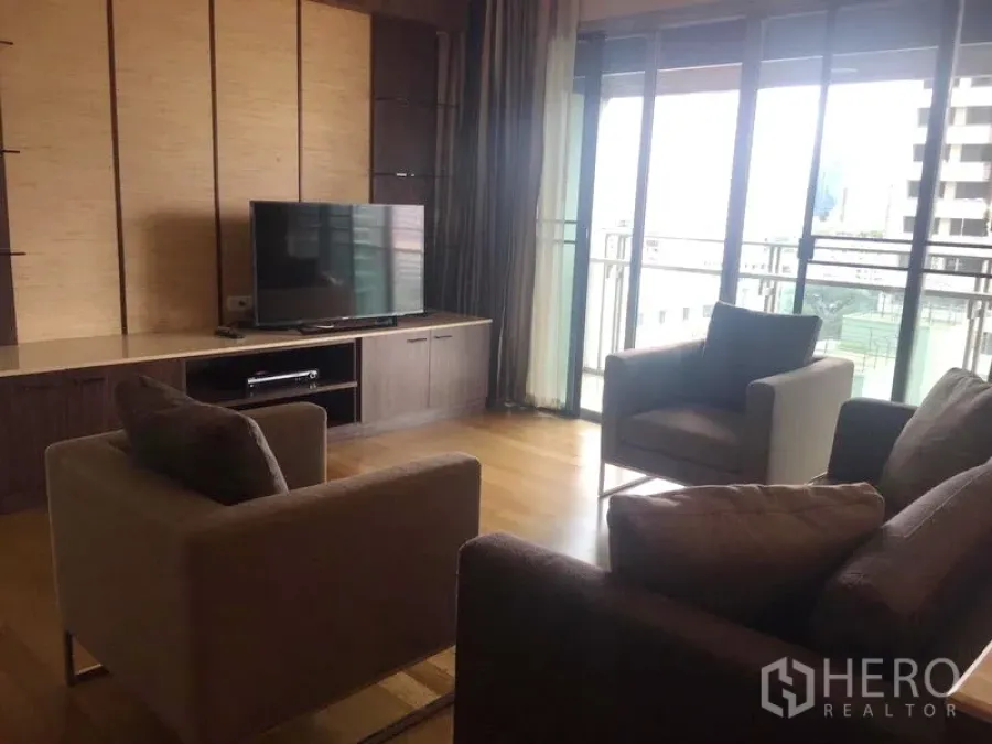 Condominium for rent in Watthana, Bangkok - Bright living room with wood floors, TV wall unit and sliding doors to a balcony in a Sukhumvit condo.
