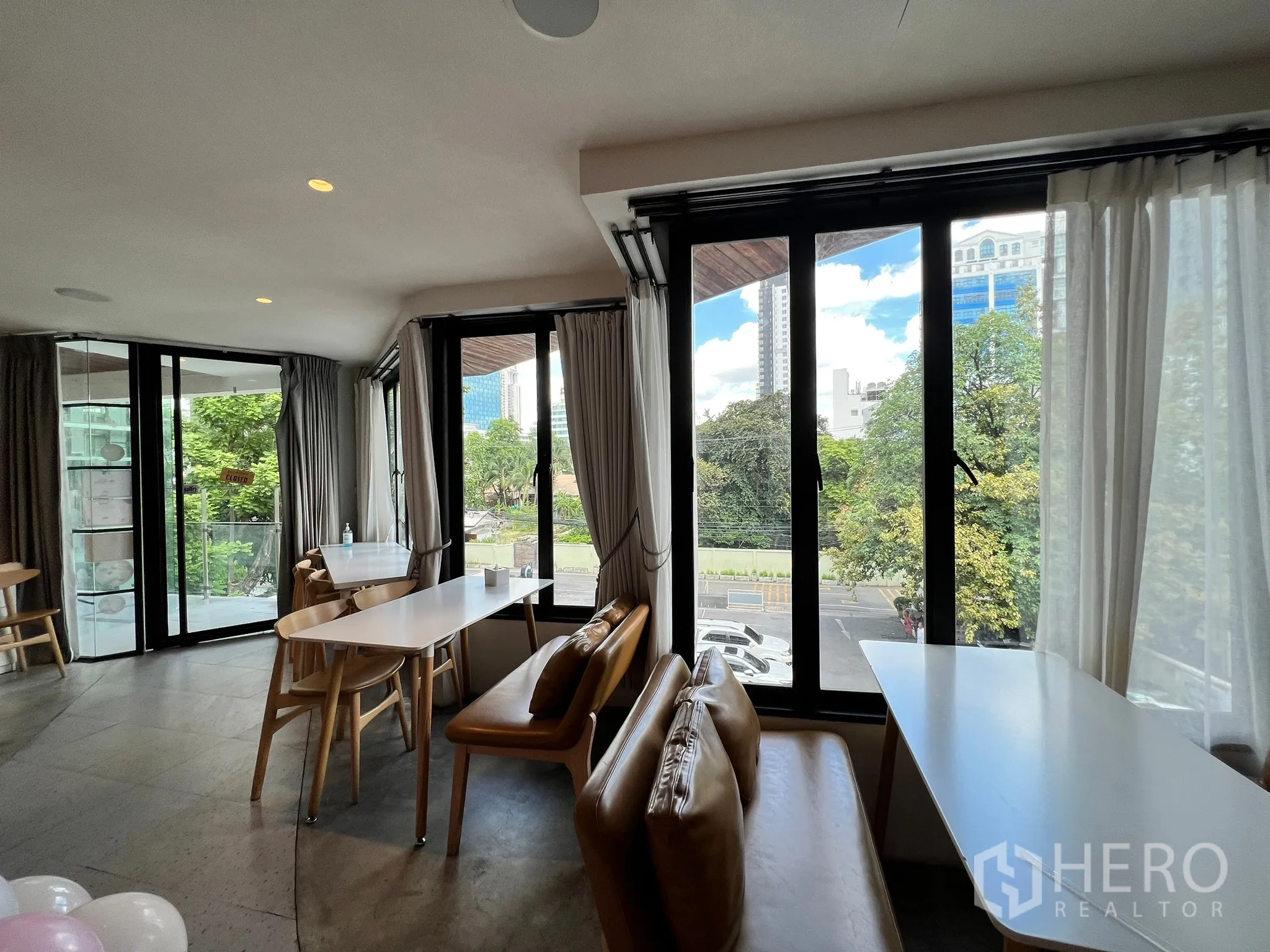 Retail Space for rent in Watthana, Bangkok - Lounge-style seating by floor-to-ceiling windows overlooking trees and Bangkok skyline.