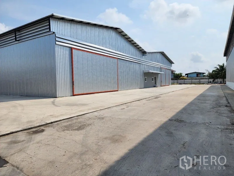 Factory for rent in Mueang Samut Sakhon, Samut Sakhon - Side exterior of the warehouse with a long driveway and truck maneuvering space.