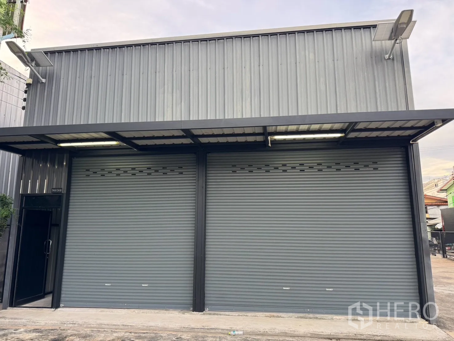 โกดัง for rent in Suan Luang, Bangkok - ด้านหน้าโกดังพร้อมประตูม้วนคู่ หลังคากันสาด และลานคอนกรีต