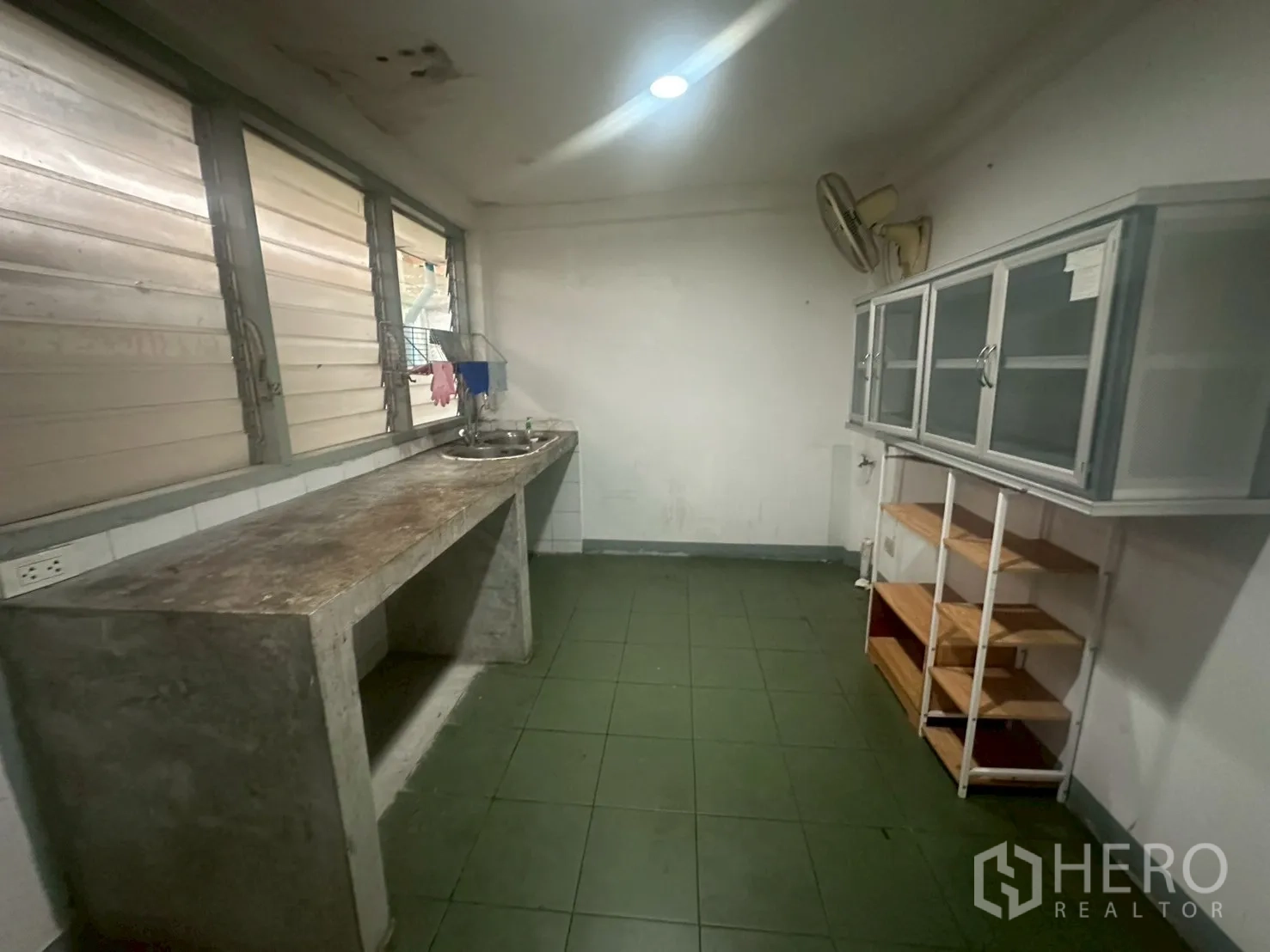 Detached House for rent in Watthana, Bangkok - Basic Thai kitchen with concrete countertop, sink and wall cabinets.