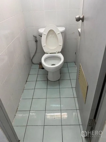 Factory for rent in Lat Lum Kaeo, Pathum Thani - Compact restroom with toilet, handheld bidet and tiled floor.