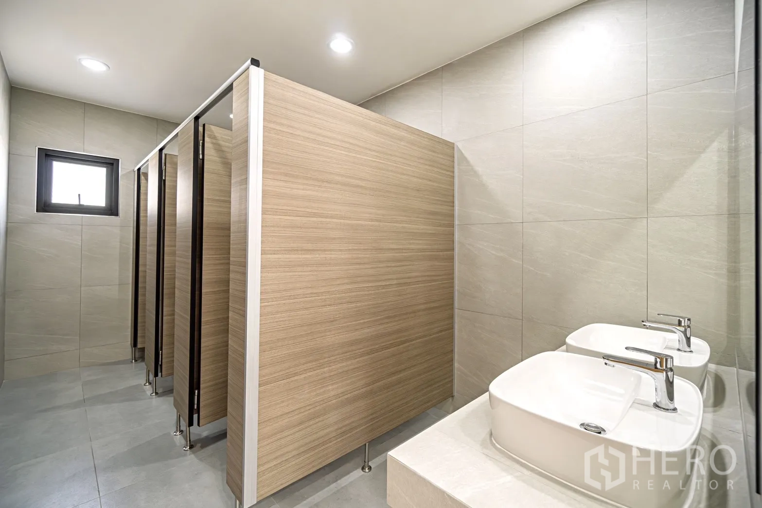 Factory for rent or sale in Lam Luk Ka, Pathum Thani - Clean restroom with multiple stalls and twin countertop washbasins.