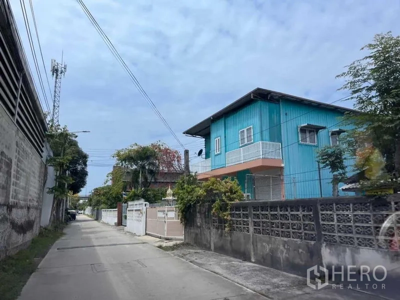 Warehouse for rent in Bang Phli, Samut Prakan - Quiet lane outside the property showing neighborhood houses and concrete road.