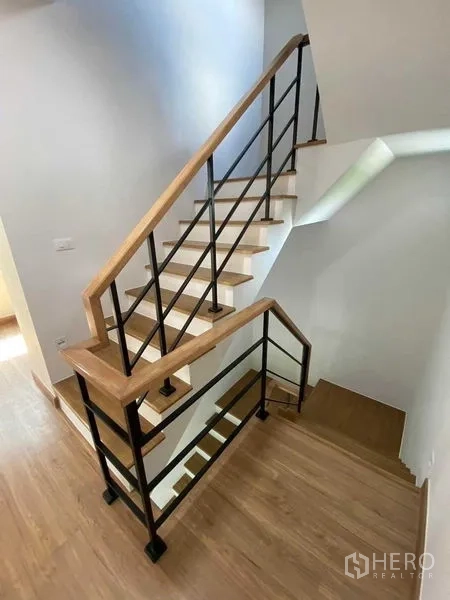 Detached House for rent in Khan Na Yao, Bangkok - Wooden staircase with black metal balustrade in a modern three‑storey home.
