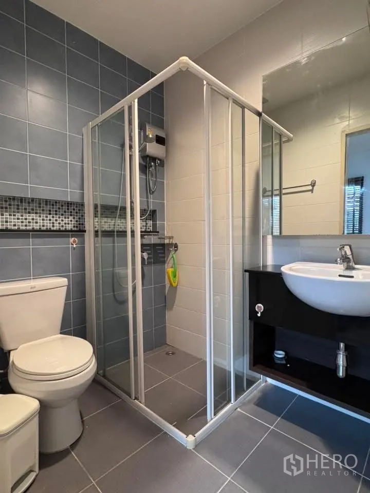Townhouse for rent in Phra Khanong, Bangkok - Bathroom with glass shower enclosure, vanity, and toilet.