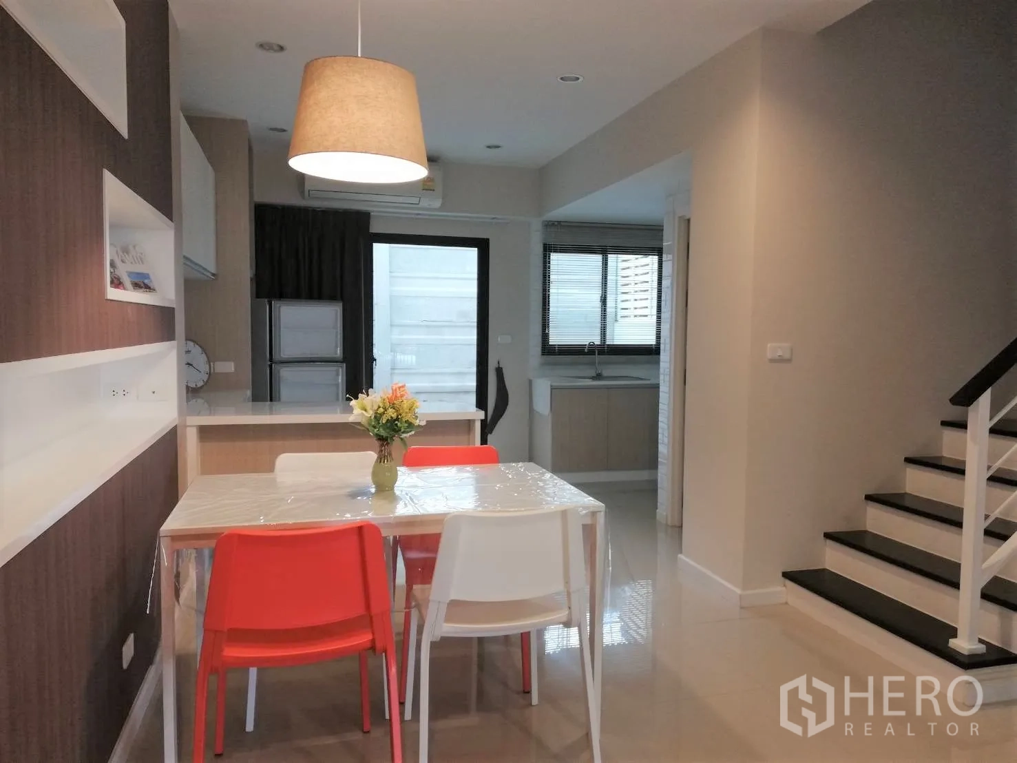 Townhouse for rent in Bang Kapi, Bangkok - Open-plan dining area with pendant light, four chairs, pantry counter and staircase beside the kitchen.