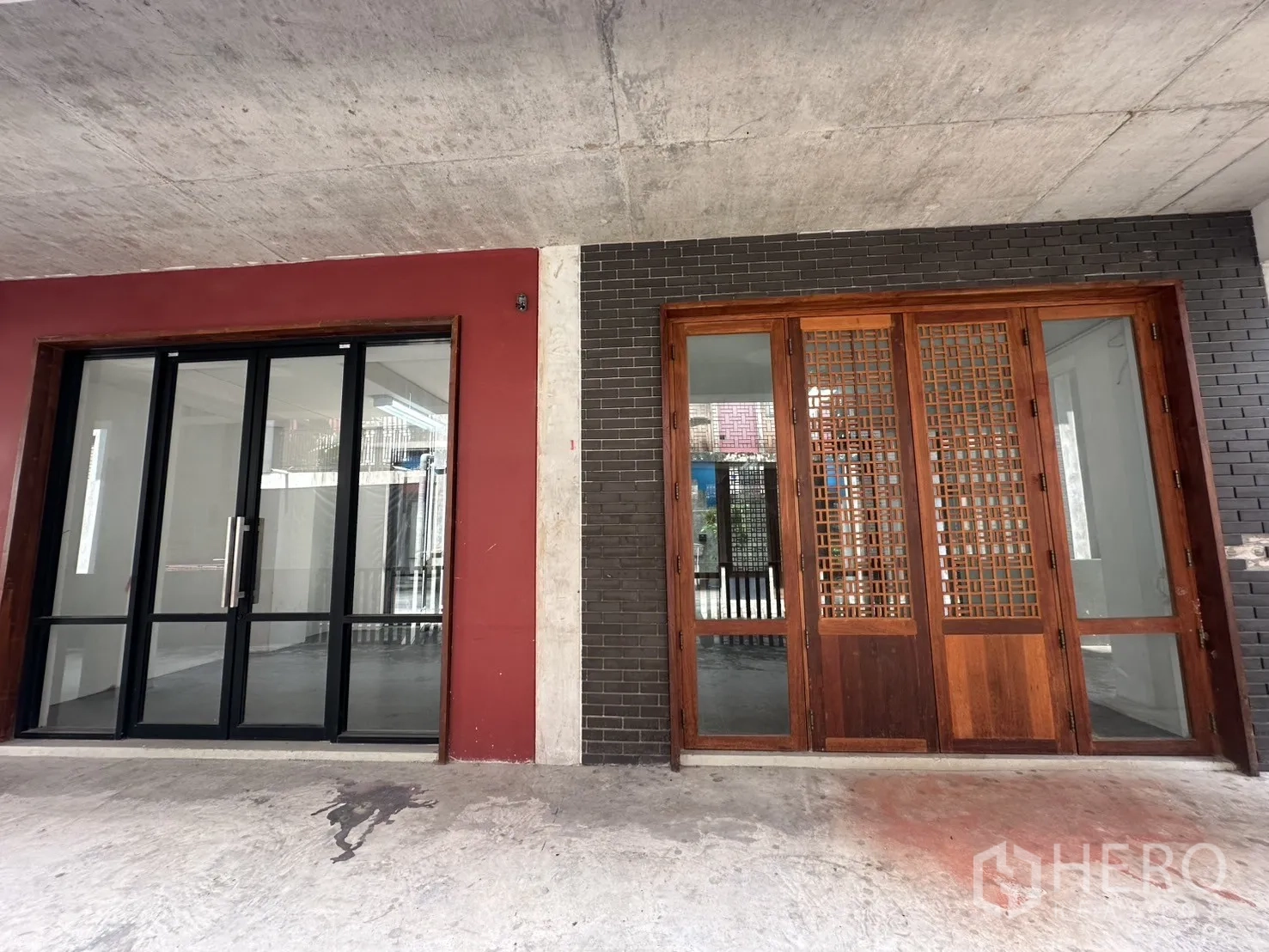 Home Office for rent in Pathum Wan, Bangkok - Ground-floor entrance showing a black-framed glass sliding door beside wooden lattice doors.