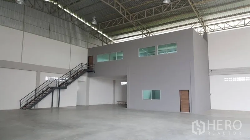 Factory for sale in Bang Sao Thong, Samut Prakan - Internal mezzanine office block with windows and a metal staircase inside the warehouse.