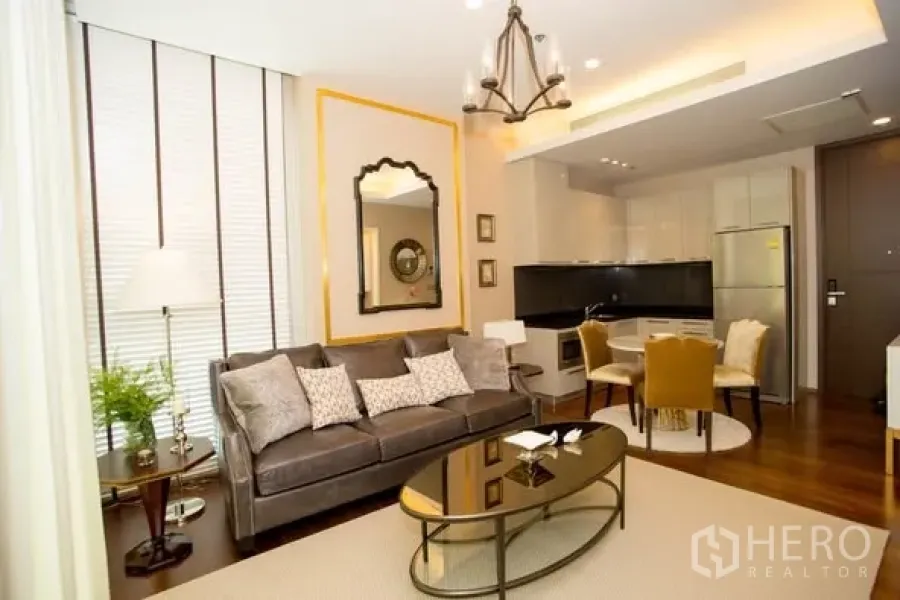 คอนโด ให้เช่าในWatthana, Bangkok - ห้องนั่งเล่นคอนโดทองหล่อแบบเปิดโล่ง โซฟาสีเทา กระจกกรอบทอง โคมระย้า และครัวพร้อมโต๊ะทานอาหาร