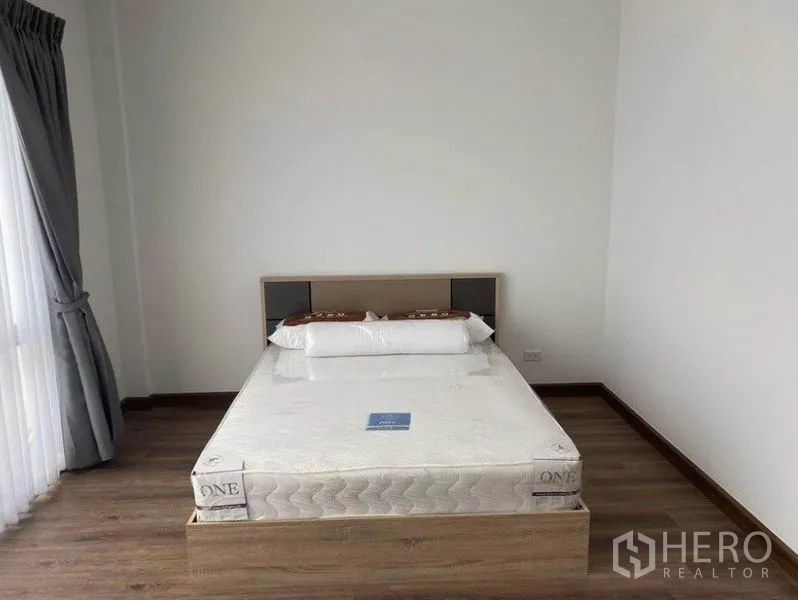 Townhouse for rent in Bang Na, Bangkok - Furnished bedroom with double bed beside a large window and curtains.