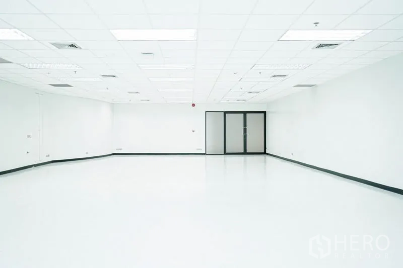 Office Space for rent in Watthana, Bangkok - Spacious empty office with white floors, grid ceiling and glass double doors.
