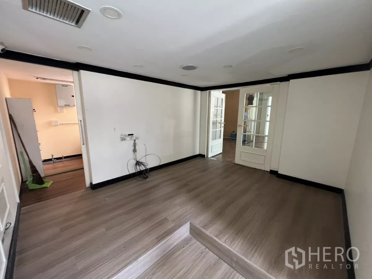 Retail Space for rent - Back office room with exposed wiring and double doors to the main area.