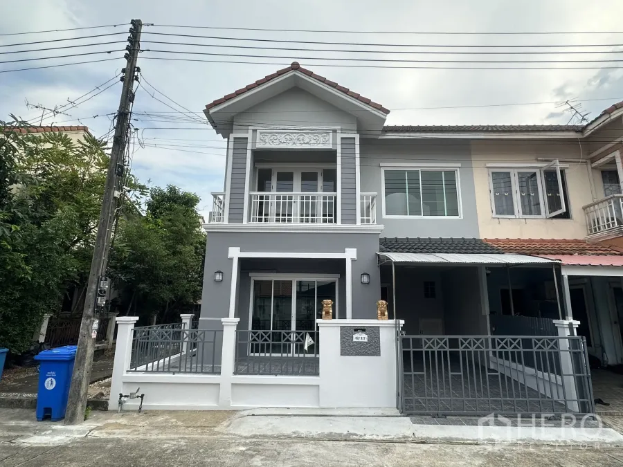 Townhouse for sale in Lam Luk Ka, Pathum Thani - Freshly renovated corner townhouse facade with balcony, gated terrace and carport.