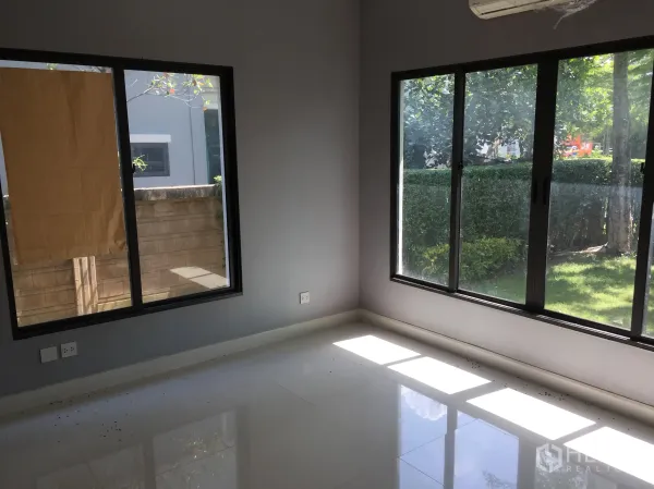 Detached House for rent or sale in Bang Kapi, Bangkok - Ground-floor bedroom with dual-aspect windows overlooking the lawn.