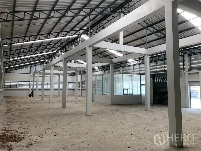 Factory for rent in Bang Bua Thong, Nonthaburi - Angled view of open production floor with skylights and a glass office room.