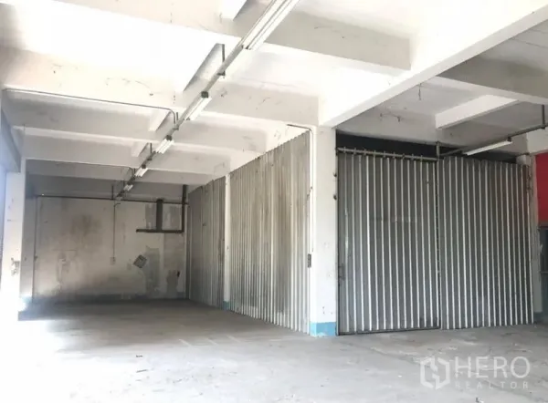 คลังสินค้า ให้เช่าในBueng Kum, Bangkok - พื้นที่เก็บของพร้อมประตูเหล็กบานสไลด์ เพดานคานคอนกรีตและไฟยาวต่อเนื่อง