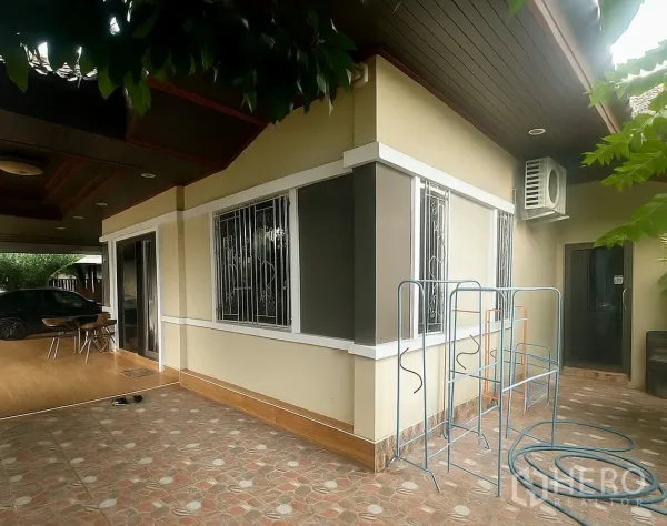 Detached House for sale in Pathum Thani - Side patio with sliding door, barred windows and exterior AC units under the eaves.
