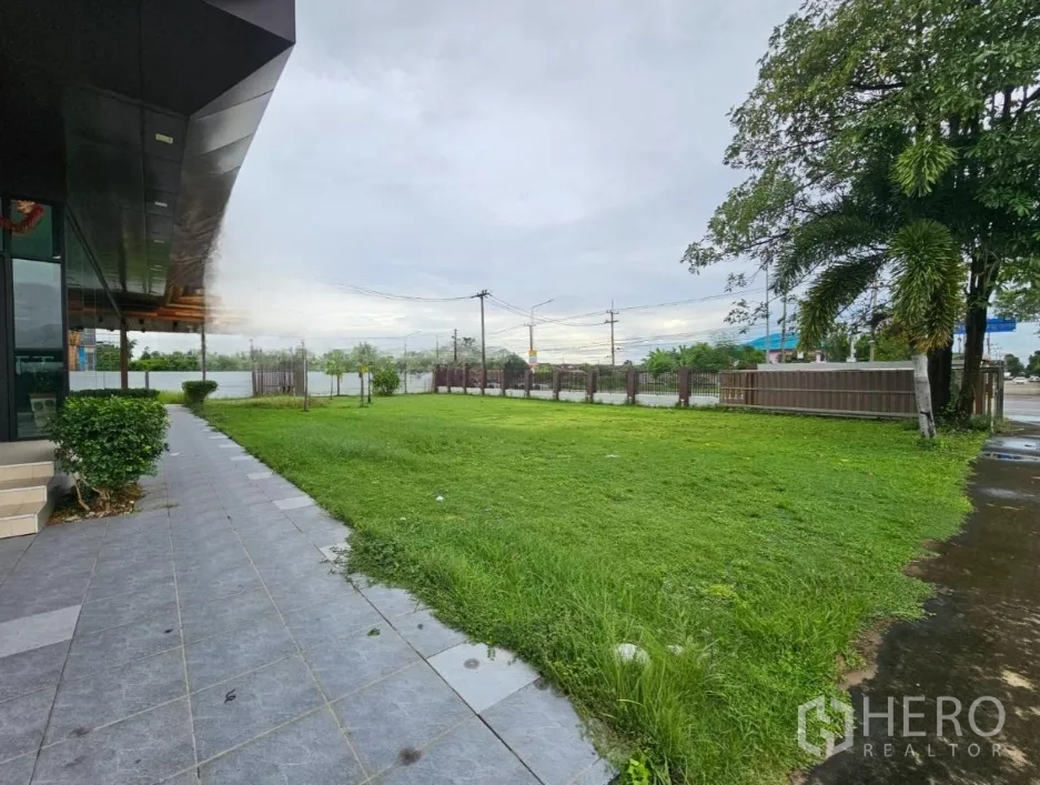 Warehouse for rent in Lam Luk Ka, Pathum Thani - Lawn area alongside office façade and boundary fence at the site frontage.
