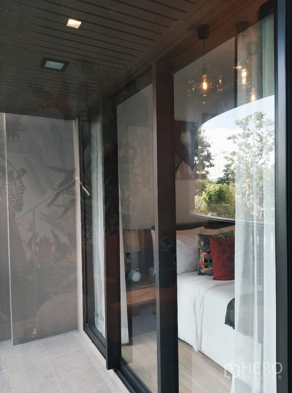Condominium for rent in Watthana, Bangkok - Sliding glass doors from the bedroom open to a balcony with leafy views.