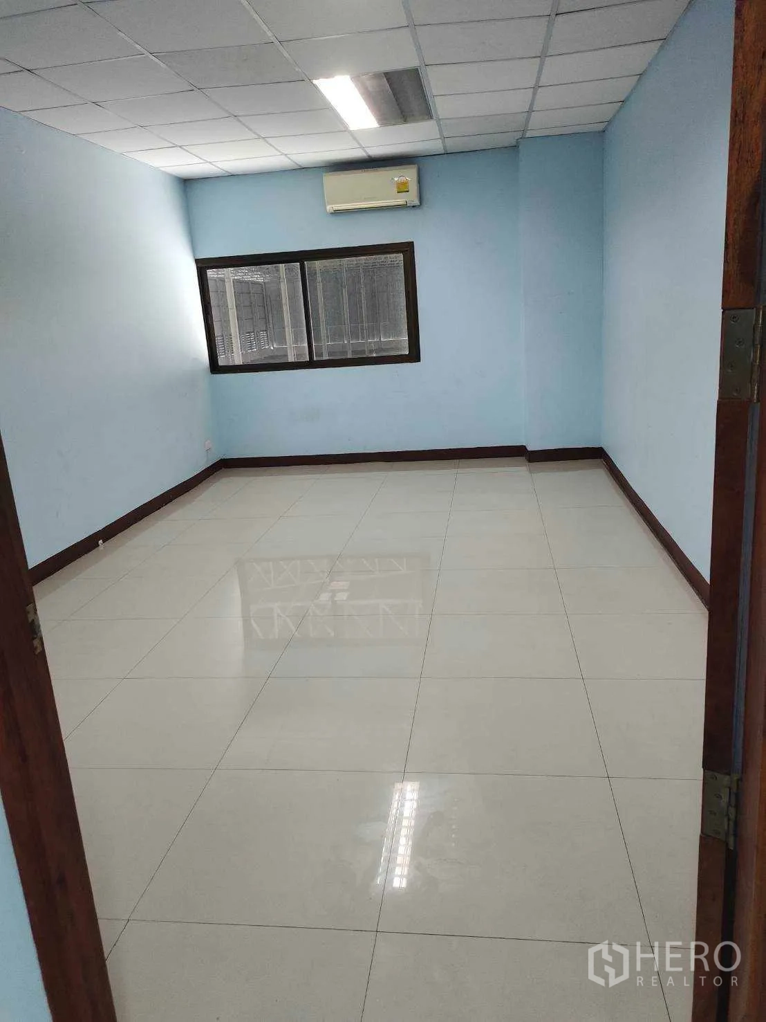 Factory for sale in Nikhom Phatthana, Rayong - Compact air-conditioned office room with tiled floor and window.