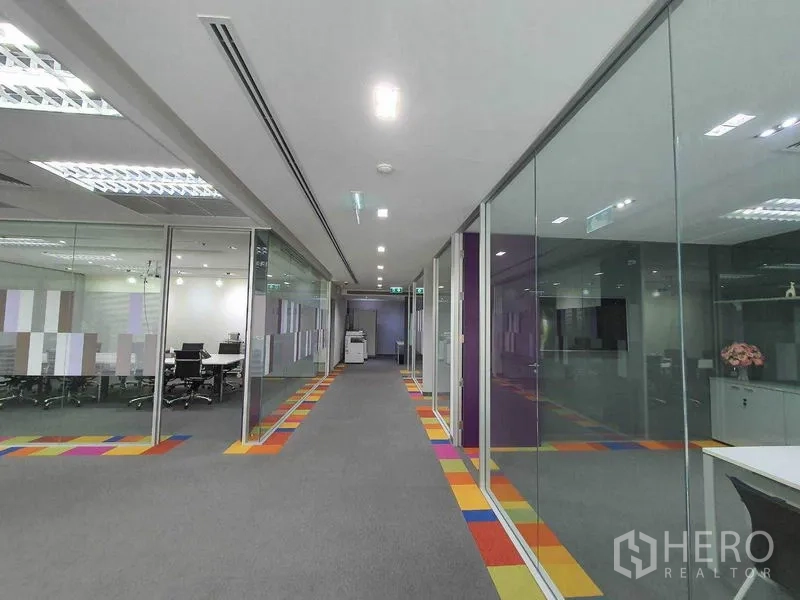 Office Space for rent in Ratchathewi, Bangkok - Wide corridor lined with glass-partitioned meeting rooms and colorful floor accents.