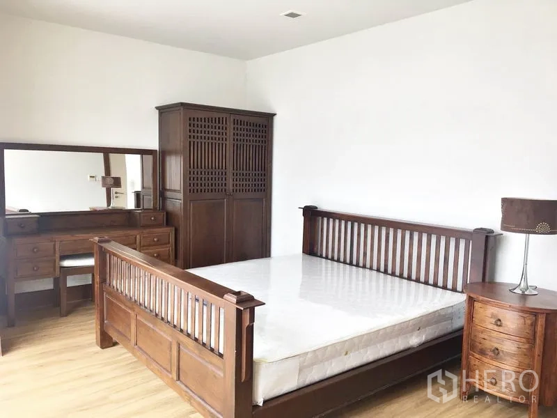 Condominium for rent in Khlong Toei, Bangkok - Master bedroom with wooden bed frame, wardrobe and dressing table.