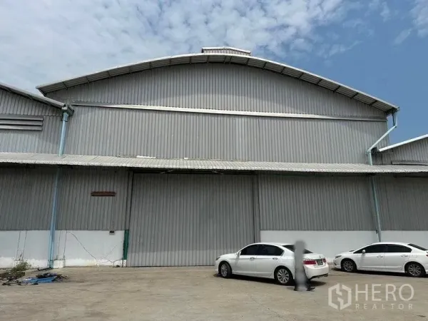 Warehouse for rent in Bang Pa-in, Phra Nakhon Si Ayutthaya - Front view of a large steel-clad warehouse with wide sliding door and parking area.