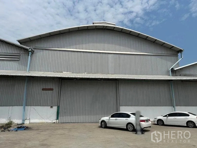 Warehouse for rent in Bang Pa-in, Phra Nakhon Si Ayutthaya - Front view of a large steel-clad warehouse with wide sliding door and parking area.