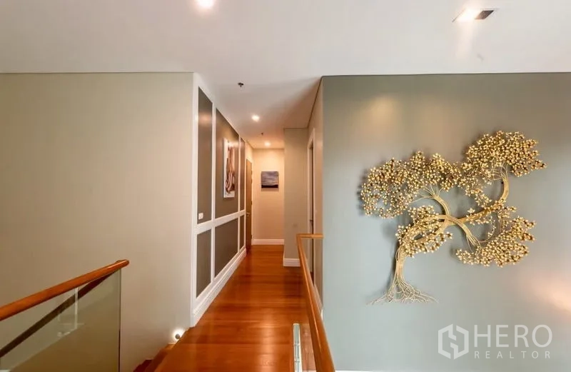 Condominium for rent in Khlong Toei, Bangkok - Hallway on the upper floor with wooden floors and decorative tree wall art.