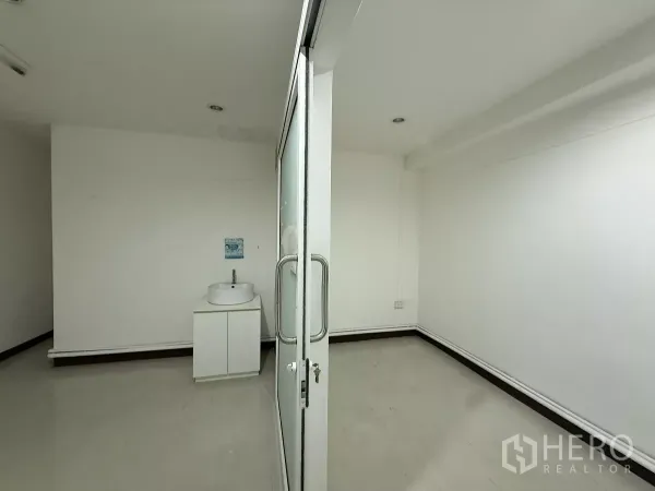 Office Space for rent in Din Daeng, Bangkok - Compact white office with sliding glass door and a vanity sink cabinet.