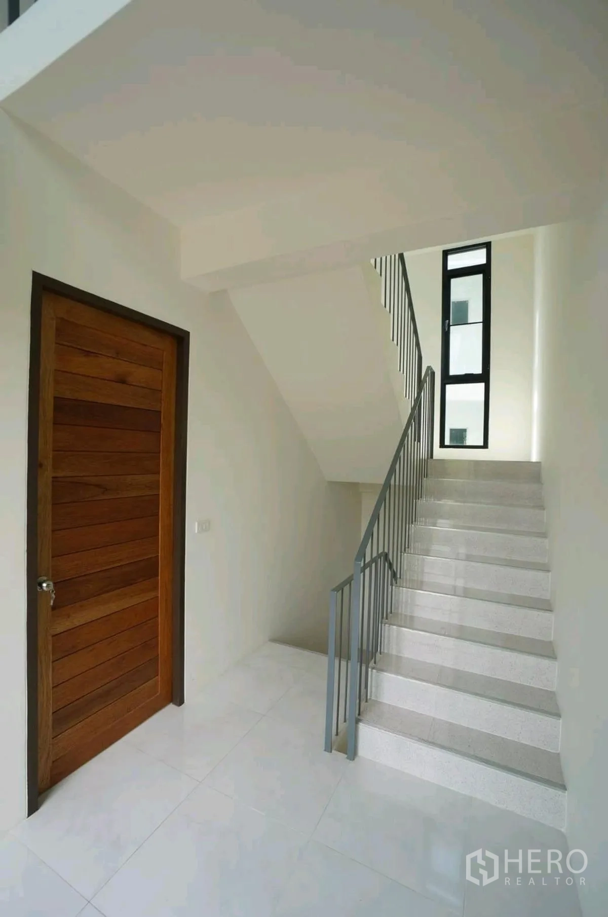 Home Office for rent in Chatuchak, Bangkok - Landing with a wooden door beside the staircase and a tall narrow window.