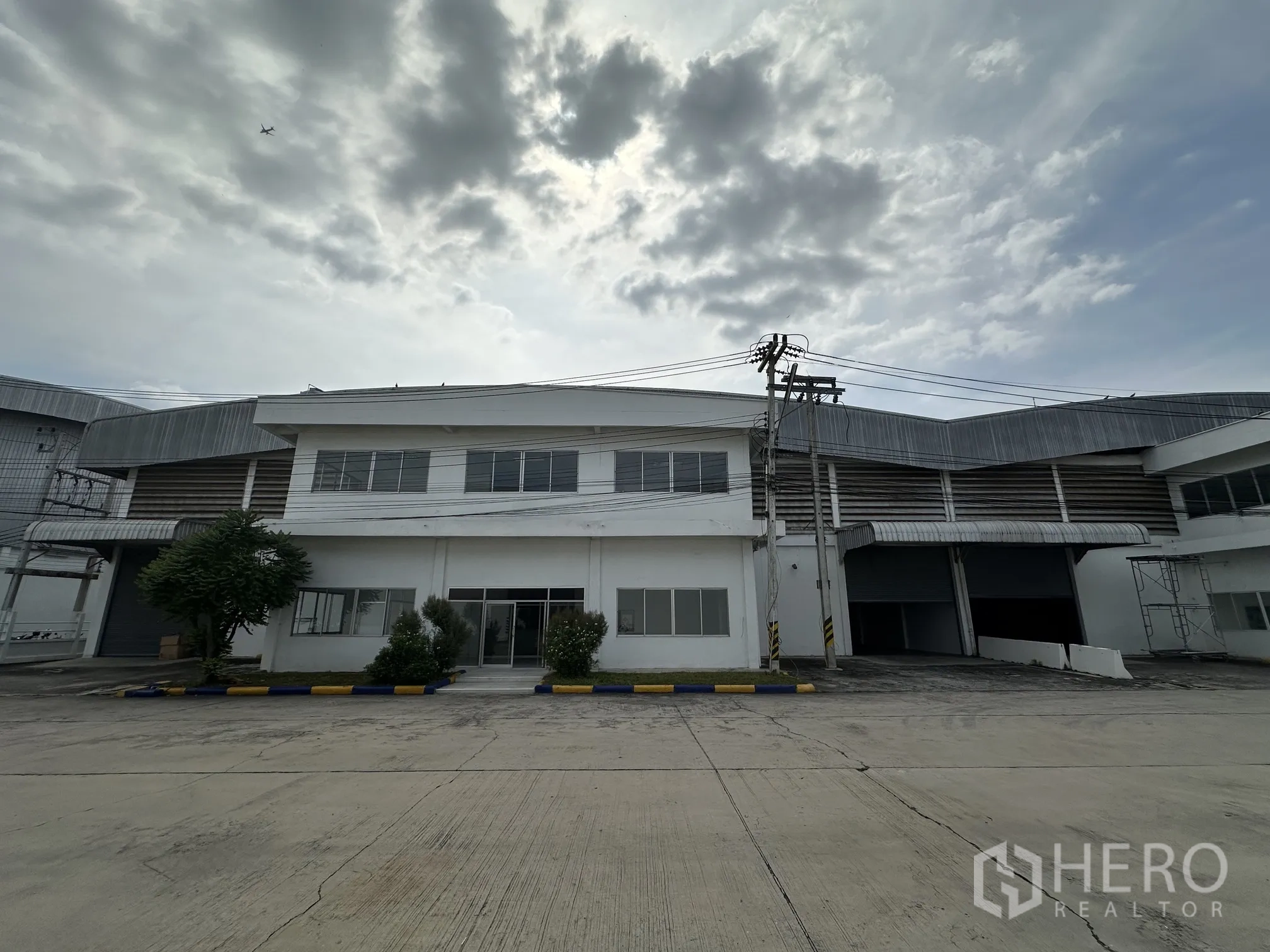 仓库 for rent in Wang Noi, Phra Nakhon Si Ayutthaya - 两层办公楼与相连仓库正面，可见卷帘门装卸区。