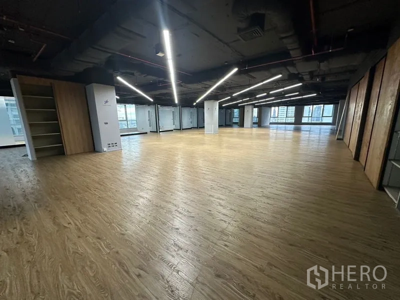 Office Space for rent in Bang Rak, Bangkok - Open-plan floor with wood floors, ceiling light strips, and shelving units.