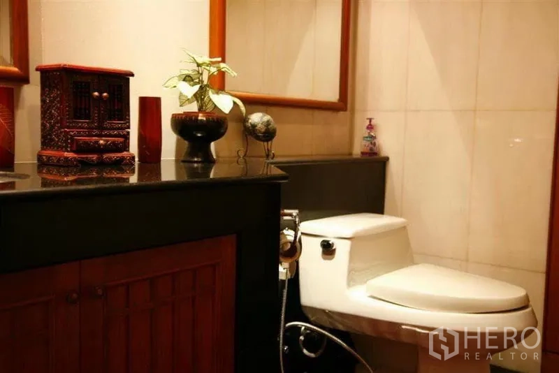 Detached House for rent in Phaya Thai, Bangkok - Guest bathroom featuring a dark stone vanity, large mirror and toilet.