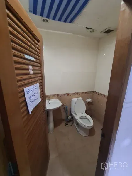 Office Space for rent in Bang Rak, Bangkok - Private restroom with toilet, sink and tiled walls inside the office.