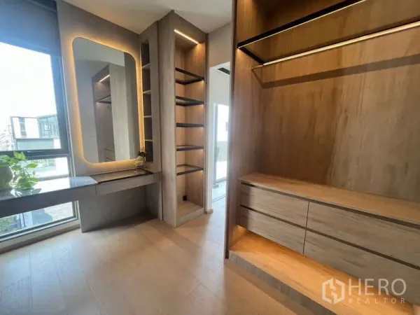 Townhouse for rent in Phra Khanong, Bangkok - Custom walk-in wardrobe with illuminated shelving, drawers and a vanity in the townhouse.