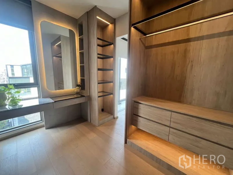 Townhouse for rent in Phra Khanong, Bangkok - Custom walk-in wardrobe with illuminated shelving, drawers and a vanity in the townhouse.