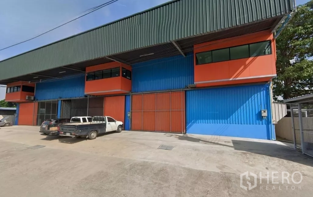 Warehouse for rent in Lat Krabang, Bangkok - Colorful steel-structure warehouse exterior in Lat Krabang with wide sliding doors and parking yard.