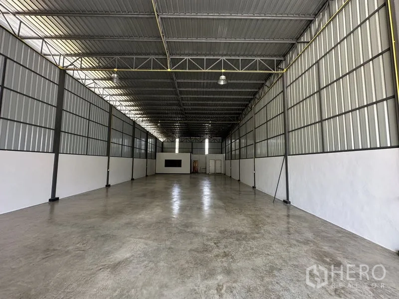 Warehouse for rent in Khlong Sam Wa, Bangkok - Long central aisle inside the warehouse with bright lighting and clean white walls.