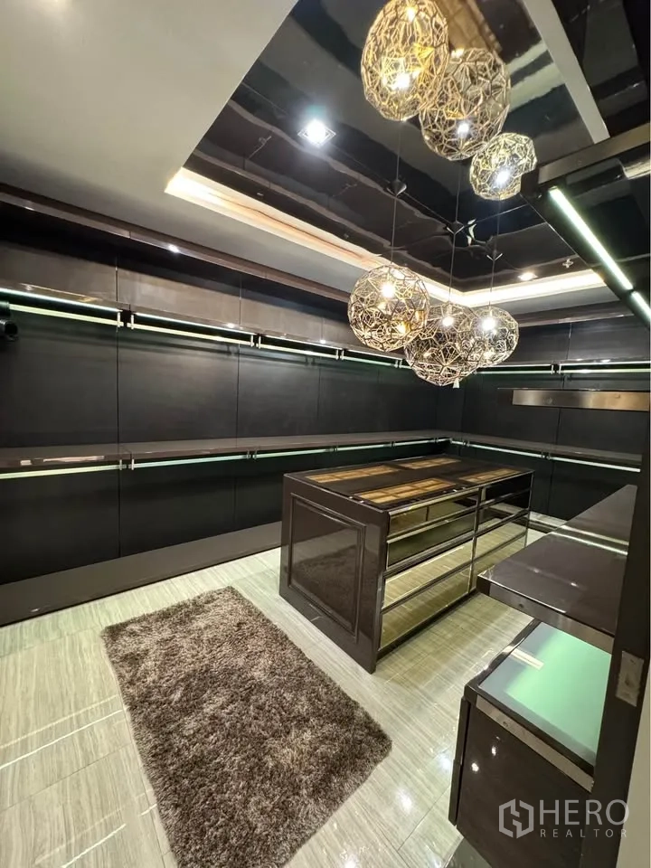 Condominium for rent or sale in Khlong Toei, Bangkok - Spacious dressing room with island drawers, hanging rails and a plush rug.