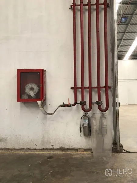 Warehouse for rent in Bang Bua Thong, Nonthaburi - Close-up of indoor fire safety system with red pipes, hose cabinet and extinguishers.