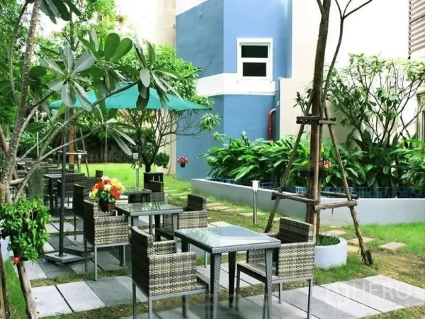 Shophouse for rent or sale in Khlong Toei, Bangkok - Garden terrace with rattan tables, umbrellas, and lush greenery beside the building.