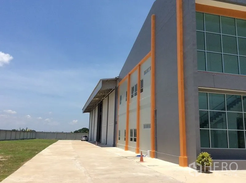 Factory for sale in Bang Sao Thong, Samut Prakan - Side elevation showing warehouse bays, driveway and lawn.