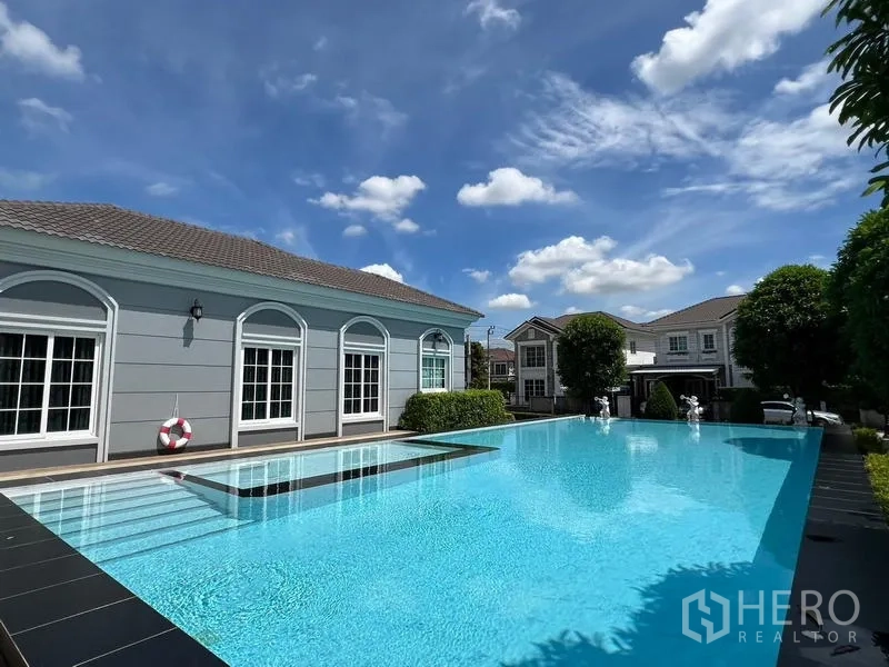 Detached House for rent or sale - Outdoor swimming pool beside the clubhouse under a blue sky.