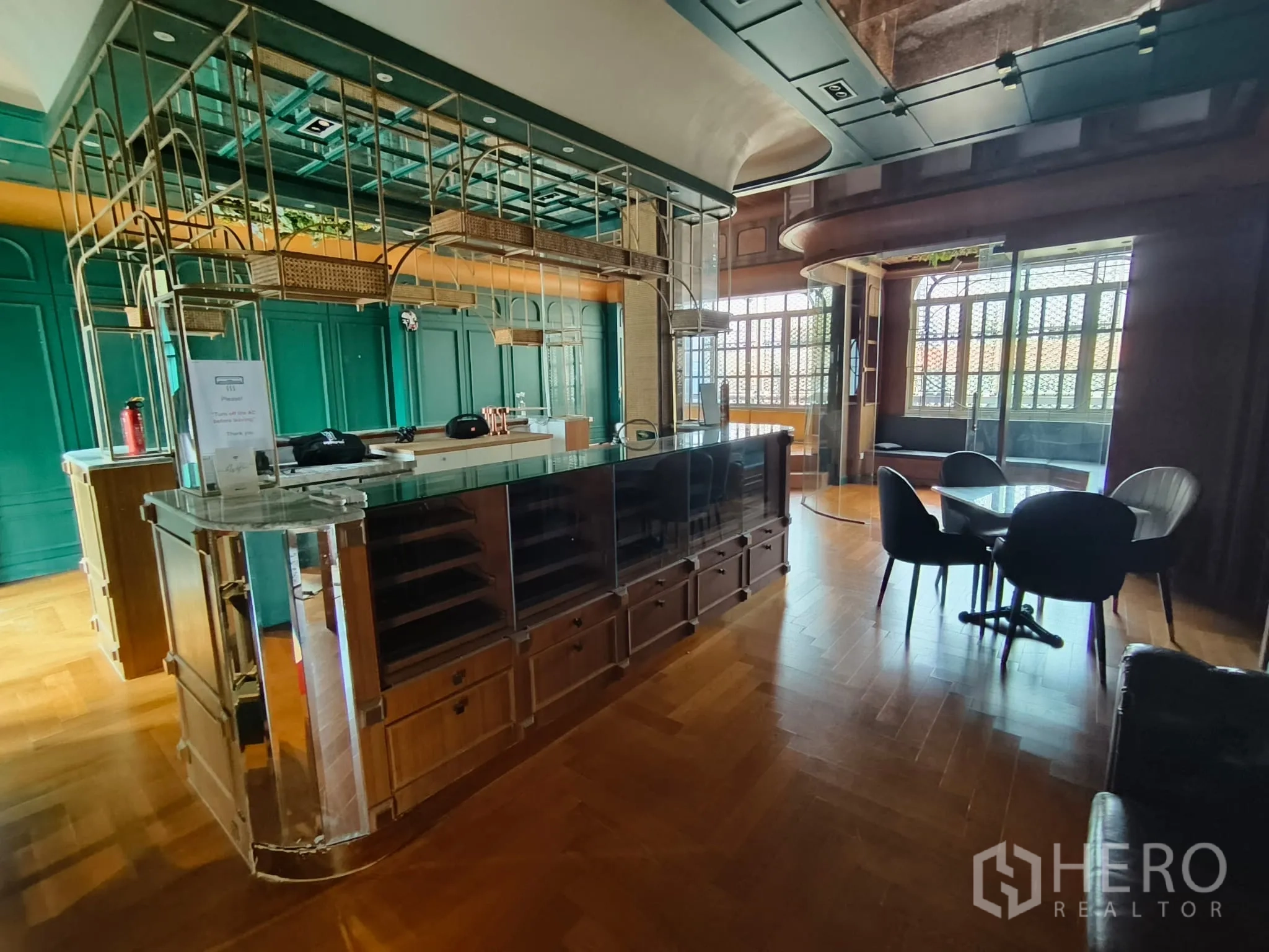 Shophouse for rent in Watthana, Bangkok - Lounge area with glass counters, metal shelving, round table and arched windows.