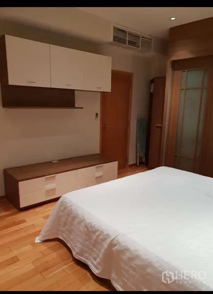 Condominium for rent - Bedroom angle showing storage cabinets, low TV console and wooden flooring.