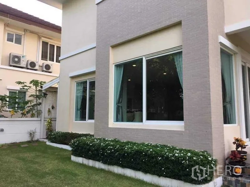 Detached House for sale in Bang Kruai, Nonthaburi - Ground-floor corner with large picture windows, curtains and a small landscaped garden.