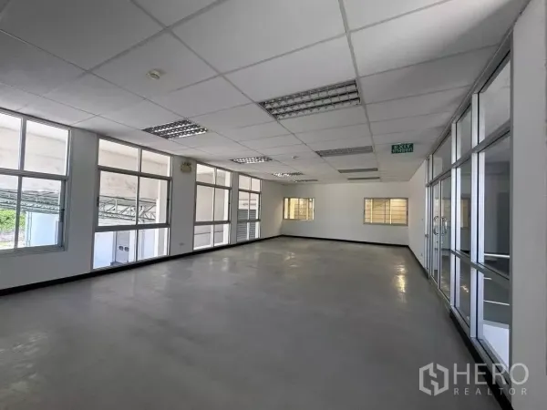 Factory for rent in Si Racha, Chon Buri - Bright office interior with grid ceiling, fluorescent lighting and glass partitions.